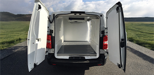 Žena pomáhá muži na invalidním vozíku nastoupit do automobilu.